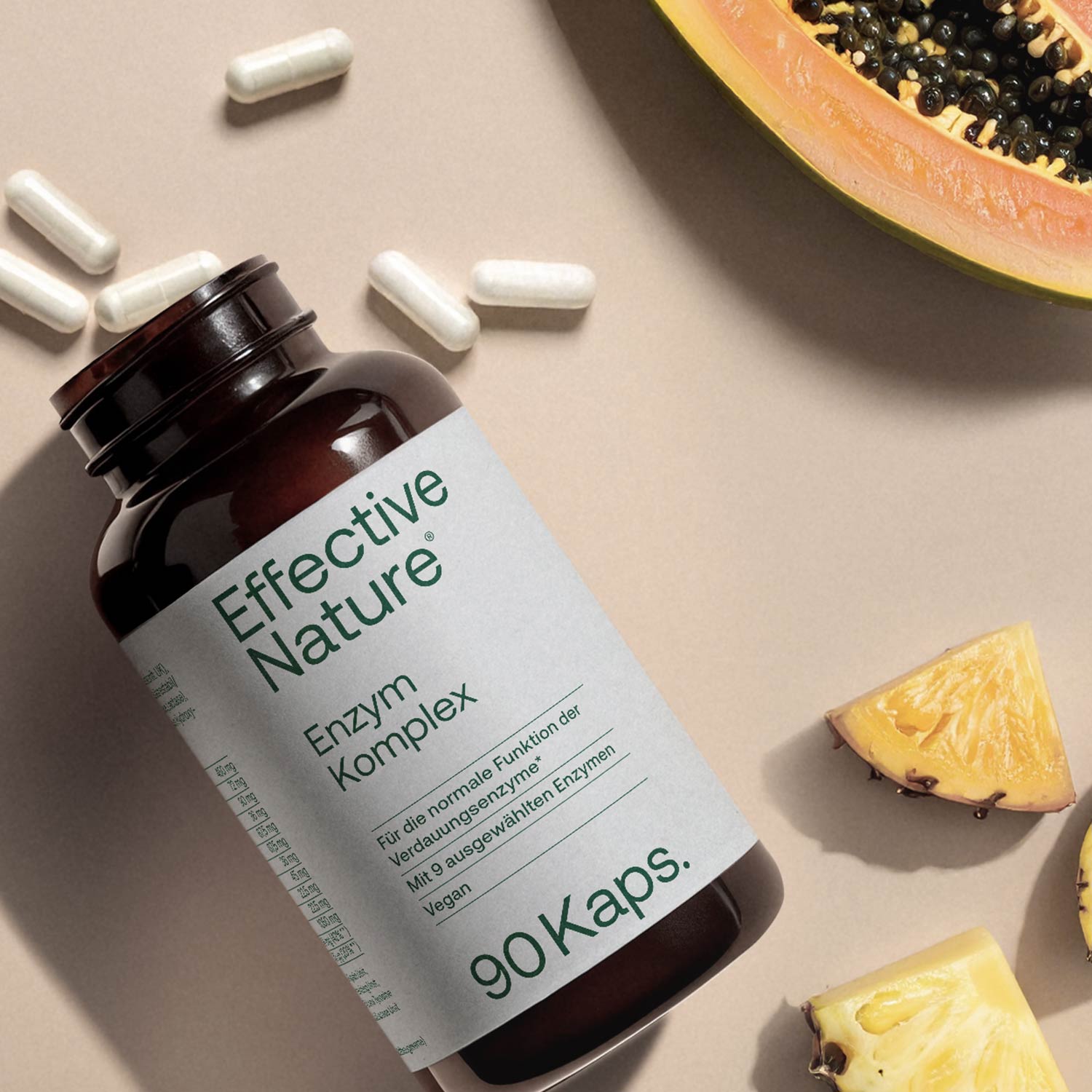 Flasche mit Effective Nature Enzym Komplex Kapseln, umgeben von Papaya und Ananasstücken