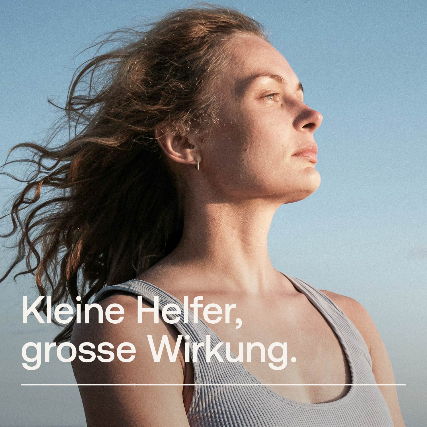 Porträt einer Frau mit wehendem Haar, die in die Ferne schaut, unter klarem Himmel