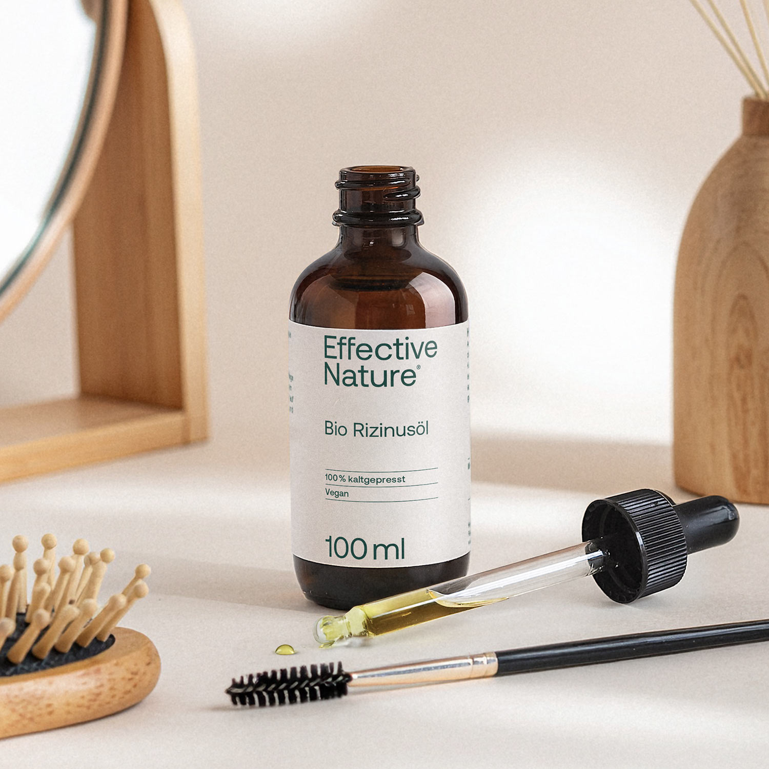 Eine Flasche Rizinusöl von Effective Nature auf einem Tisch nebst Pipette und Körperpflegeartikel