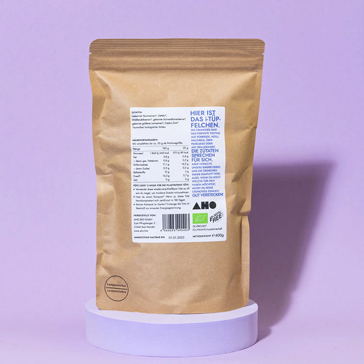 Rückansicht einer braunen Papierverpackung mit Bio-Zertifikat und Produktinformationen, lila Hintergrund