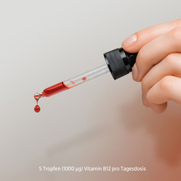 Hand mit Pipette, Tropfen Vitamin B12 Flüssigkeit