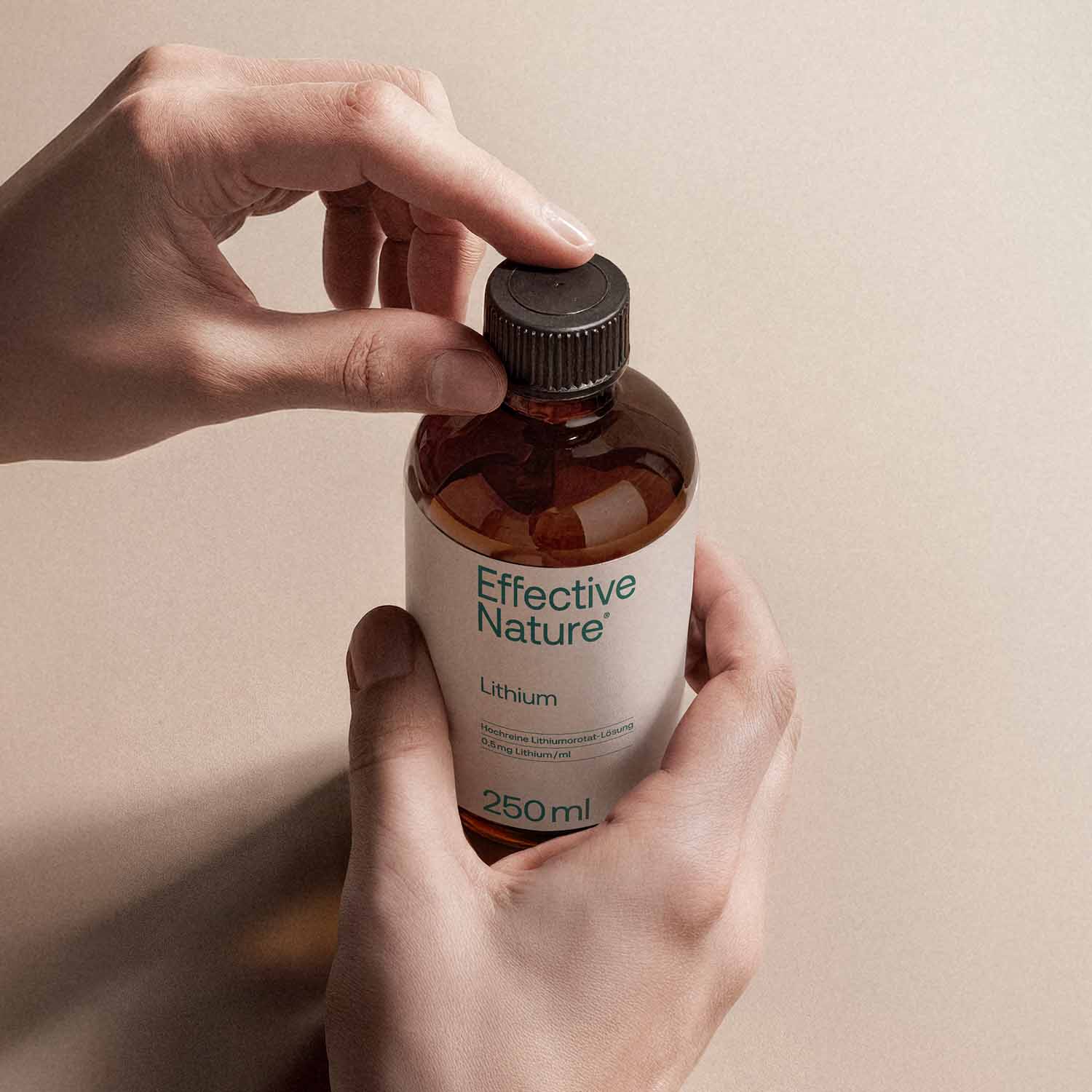 Hand hält eine Flasche Effective Nature Lithium, 250 ml, Nahrungsergänzungsmittel