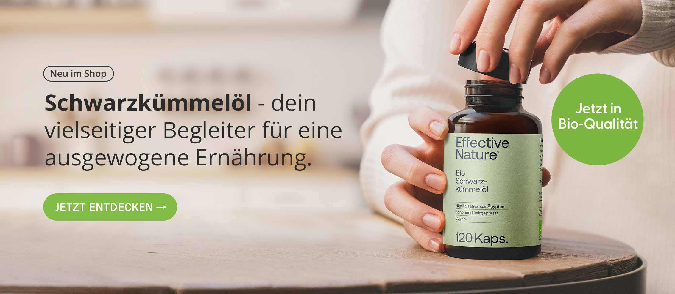 Hand hält Glas mit Bio-Schwarzkümmelöl-Kapseln von Effective Nature, beworben für ausgewogene Ernährung