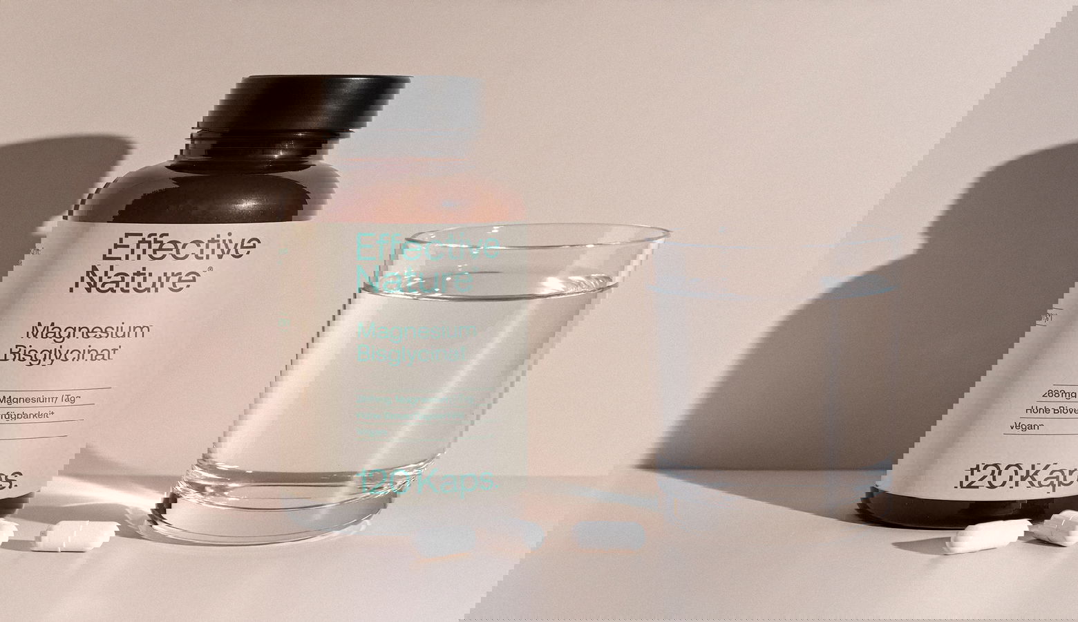 Eine Dose Magnesiumbisglycinat neben einem Glas Wasser auf einem Tisch
