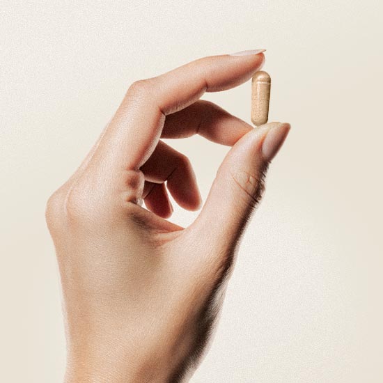 Eine Hand hält eine Kapsel zwischen Daumen und Zeigefinger