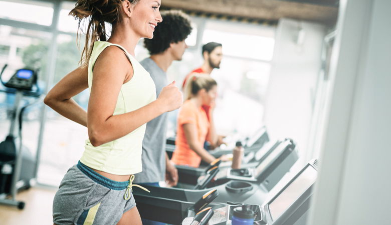 Eine Frau benutzt im Fitnessstudio das Laufband