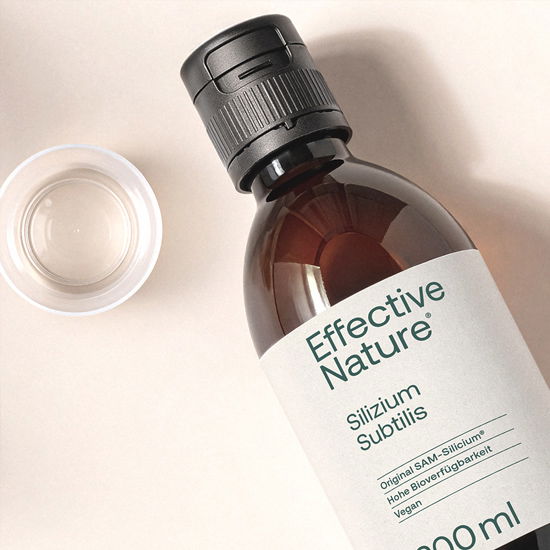 Braune Flasche mit Etikett 'Effective Nature Silizium Subtilis', 500 ml neben einem kleinen Messbecher