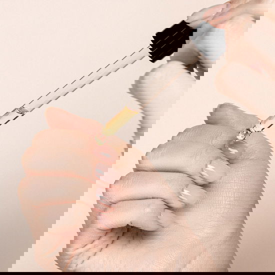 Frau tropft sich Öl auf die Fingernägel