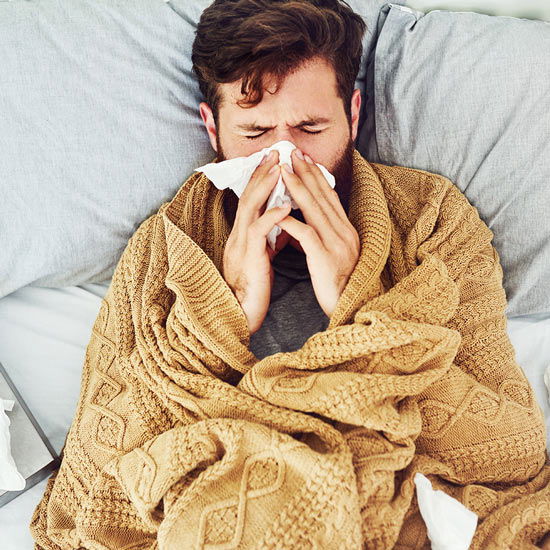 Mann mit Schnupfen im Bett