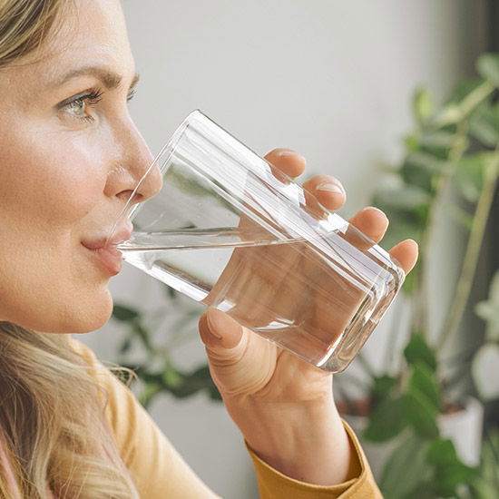 Frau trinkt Wasser mit Selen Tropfen drin